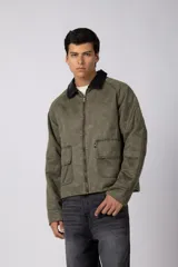 Chaqueta de estilo militar color verde oliva, confeccionada en gabardina resistente. Presenta cuello camisero en contraste color negro, cierre frontal con cremallera, dos bolsillos frontales tipo cargo con solapa y ajuste relajado.