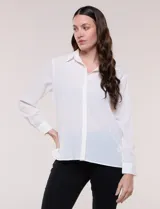 Camisa blanca de corte clásico y caída fluida, con cuello camisero tradicional, abotonadura frontal oculta y mangas largas con puños anchos.