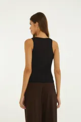 Musculosa negra con escote redondo ribeteado en encaje, detalle de botones frontales y diseño ajustado.