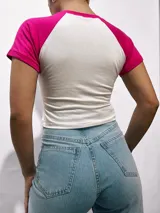 Remera corta blanca con mangas raglán de diferentes colores y estampado frontal con la leyenda "Malibu California A Beautiful Place".