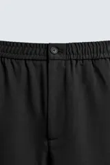 Pantalón regular fit color marrón oscuro, confeccionado en tejido con viscosa. Cuenta con cintura elástica, bolsillos delanteros y detalle de bolsillos traseros de vivo. El cierre frontal es con cremallera y botón.