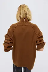 Buzo oversized de punto suave con cuello tortuga acanalado y abertura en la nuca. Presenta mangas raglán con costuras decorativas y terminaciones acanaladas en puños y bajo.