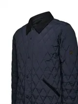 Campera acolchada azul marino con costuras en rombos, cuello de pana negro y cierre frontal con botones a presión. Incluye bolsillos laterales con ribete de pana y broches ajustables en la cintura.