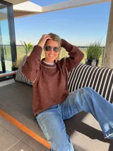 Sweater de tejido de punto color marrón, con cuello redondo y detalles de costuras bordadas a mano en color crudo en el cuello y las mangas. Presenta un diseño de corte holgado y mangas largas con puños acanalados.