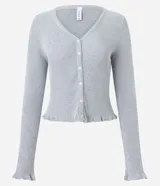 Cardigan de punto texturizado color rosado, con escote en V, cierre frontal por botones, mangas largas y acabado con volados sutiles en el ruedo y los puños.