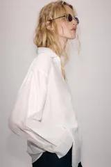 Camisa amplia de cuello solapa con escote en pico y manga larga, en tejido satinado de color bordó. Cuenta con un bolsillo de plastrón en el frente y un diseño holgado.