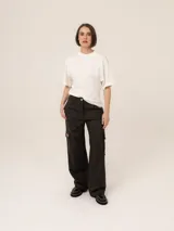 Pantalón cargo de corte recto y tiro medio, color negro, con bolsillos laterales tipo cargo y cierre frontal con botón.