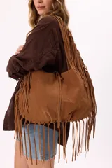 Bolso estilo hobo de símil gamuza color marrón, con diseño amplio y detalle de flecos largos en todo el contorno y las correas.