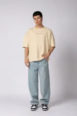 Remerón de corte oversized confeccionado en tejido rústico, con cuello redondo y mangas cortas. Presenta un diseño minimalista con una pequeña estampa frontal centrada en el pecho.