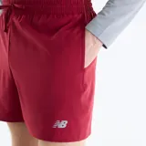 Short deportivo New Balance color bordó, con cintura elástica con cordón ajustable exterior, bolsillos laterales y logo reflectante en la pierna.
