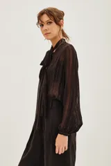 Camisa de transparencia con diseño a rayas verticales, cuello con lazo integrado y mangas largas abullonadas con puños ajustados.