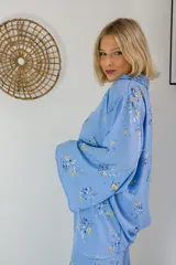 Camisa celeste con estampado floral en tonos amarillos y azules, de corte holgado y mangas anchas.