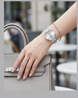 Reloj de pulsera analógico Mini Focus con caja y malla de acero inoxidable en color plateado. Presenta una esfera minimalista con un detalle circular texturizado en el centro y cierre de seguridad plegable con botón de liberación.