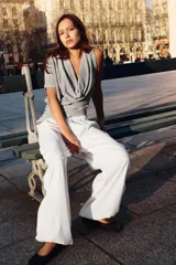 Top gris de escote drapeado, con una manga sisa y una manga corta. Presenta frunces laterales y un bajo asimétrico.