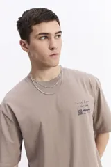 Remera de manga corta color topo, con escote redondo y fit regular. Presenta un pequeño estampado en el pecho con texto manuscrito y un código QR.