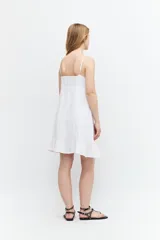 Vestido corto blanco de lino con breteles finos, corte recto y volado en el ruedo.