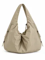 Cartera tipo shopper de color beige, confeccionada en material textil ligero, con diseño slouchy, asa de hombro integrada y detalles de cordones ajustables en los laterales.