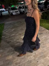 Vestido largo negro strapless de encaje con frunces en el torso, falda asimétrica en capas con volados y breteles removibles.