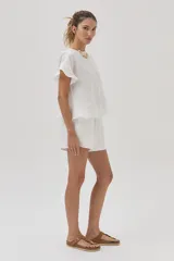 Blusa blanca de lino de manga corta, con volados en las mangas y espalda cruzada adornada con volados.