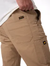 Pantalon Caterpillar de twill elastizado en color beige, con bolsillos laterales tipo utilitario, detalle de etiqueta con logo de la marca y corte ajustado.
