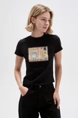 Remera de manga corta de algodón color negro, con cuello redondo a la base y estampado gráfico frontal de una carta o postal veraniega.
