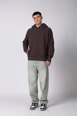 Buzo canguro de corte oversize en color gris con efecto lavado desgastado. Presenta diseño con recortes horizontales, capucha amplia y puños acanalados con etiqueta de marca en la manga.