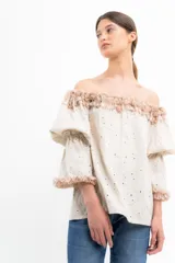 Blusa color crema con pequeños lunares marrones, escote off-shoulder con volados y mangas 3/4 abullonadas con volados en los puños.