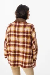 Chaqueta de corte holgado con estampado de cuadros en tonos beige, marrón y amarillo. Presenta cuello camisero en pana marrón, cierre frontal con botones y mangas largas con puños abotonados.