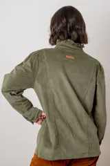 Camisa de pana color verde oliva, con cuello alto con volados, cierre frontal de botones y mangas largas con puños.