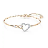 Brazalete rígido dorado con dije de corazón y símbolo de infinito con cristales blancos.