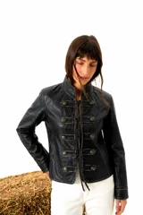 Chaqueta de estilo militar confeccionada en cuero negro con acabado artesanal gastado. Presenta cuello mao, cierre frontal con cordones y botones metálicos decorativos dispuestos en filas dobles.