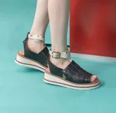 Sandalias de cuero vacuno negro con semi plataforma, diseño pintado a mano en el frente y tira al tobillo con hebilla metálica.