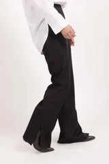 Pantalón sastrero de tiro alto y corte recto con caída amplia, confeccionado en tela de sastre color negro.
