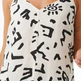 Vestido corto blanco con estampado de símbolos abstractos en negro, breteles finos y escote en V.
