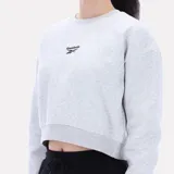 Buzo Reebok de corte cropped color gris melange, con cuello redondo, mangas largas y pequeño logo bordado en el centro del pecho.