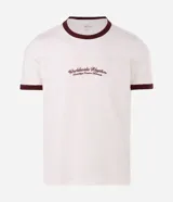 Remera estilo baby tee de color blanco crudo, con cuello redondo y ribetes en contraste de tono bordó. Presenta mangas cortas y una estampa frontal con la inscripción "Worldwide Rhythm".