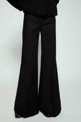 Pantalón de tiro alto con diseño flare, confeccionado en tela de color negro. Presenta cinco bolsillos, cintura con trabillas y cierre frontal con cremallera y botón.