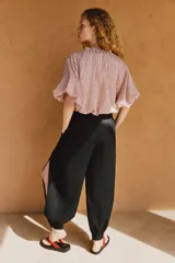 Pantalón bombacho de tiro medio confeccionado en lino, color negro, con pernera abullonada y bajo acabado en puño con botón.