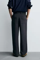Pantalón de vestir negro, corte recto y relajado, con cintura elástica, cierre frontal con cremallera y botón, bolsillos delanteros y bolsillos traseros de plastrón.