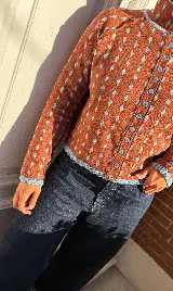 Cardigan reversible de punto con estampado de rombos pequeños, cuello alto y cierre frontal completo con botones. Presenta detalles de ribetes en color contrastante en cuello, puños y cartera de botones.