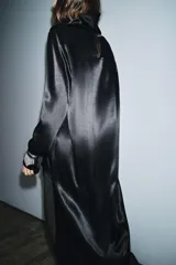 Blusa de Zara Woman Collection confeccionada en viscosa, con cuello alto, manga larga y diseño asimétrico en el bajo. Presenta un acabado satinado y cierre en la espalda.