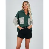Sobre camisa de pana blanca con detalles en animal print en los bolsillos frontales y en las mangas. Presenta cuello inglés, cierre frontal con botones y corte holgado.
