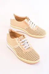 Zapatillas acordonadas color dorado con capellada de cuero calado, base blanca y detalles en cuero blanco en el talón.