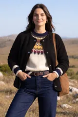 Campera de polar negro con cuello redondo, cierre frontal con botones a presión y mangas largas con puños tejidos a rayas.