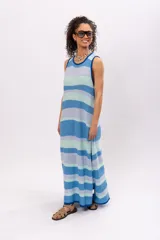 Vestido largo de algodón tejido a rayas horizontales en tonos celeste, azul y verde agua. Diseño holgado con cuello redondo y aberturas laterales en el ruedo.