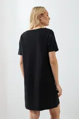 Vestido corto negro con cuello redondo, mangas cortas y detalle de flecos en el pecho.