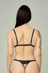 Conjunto de lencería compuesto por un corpiño triangular y una tanga regulable. Está confeccionado en microtul color tostado con detalles de encaje negro en los bordes y en las copas. El corpiño cuenta con breteles finos y la tanga presenta elásticos laterales ajustables.