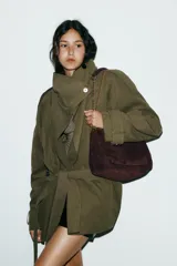 Bolso de hombro confeccionado en piel de ante color marrón, con diseño de pespuntes geométricos en la solapa. Cuenta con una correa de cadena metálica dorada y cierre imantado.