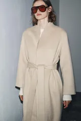 Abrigo largo de corte minimalista confeccionado en mezcla de lana, con diseño de solapas integradas, manga larga y cinturón ajustable del mismo tejido.