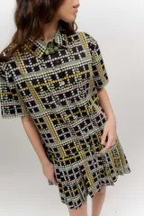 Vestido camisero corto con estampado de cuadros y flores, de manga corta, cuello camisero, cierre frontal de botones y falda tableada.